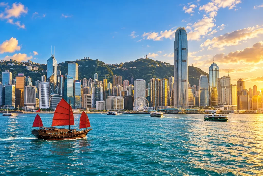 Cảng Victoria với thuyền buồm đỏ và đường chân trời Hong Kong.